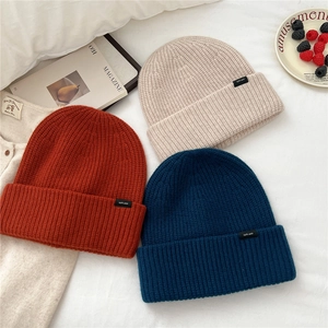 Detailed texture of thick chunky knit wool beanies in orange, beige and navy blue colors