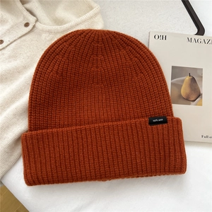 Detailed view of orange-red 100% wool knitted beanie featuring thick ribbed texture