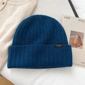 Dettaglio del berretto in lana blu navy con trama a coste ed etichetta 100% lana