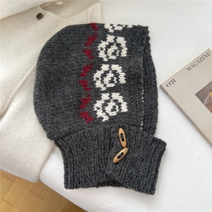 Detail of dark grey knit balaclava with white floral embroidery and wooden horn buttons