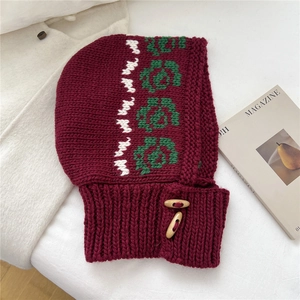 Close-up of burgundy knitted balaclava featuring floral patterns and wooden toggle buttons