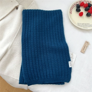Dettaglio della sciarpa in lana a maglia blu scuro con trama spessa ed etichette