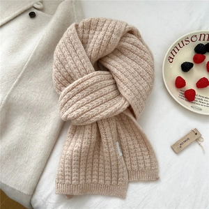 Dettaglio della sciarpa in maglia a coste color avena con etichetta di lavaggio