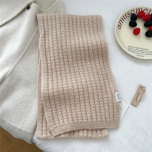 Dettaglio della sciarpa in maglia a coste beige con consistenza morbida ed etichetta
