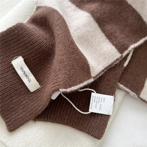 Close-up of 100% pure wool tag on brown and beige striped knitted winter scarf