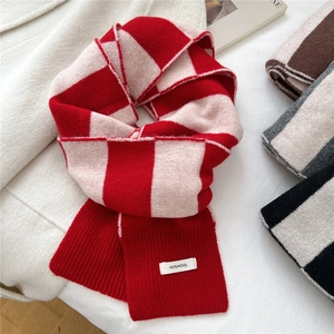 Thick red and white checkered wool scarf with 100% wool label on cozy fabric background