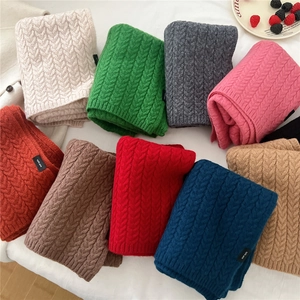 Close-up of multicolored knitted wool scarves with classic cable texture and 100% wool tags