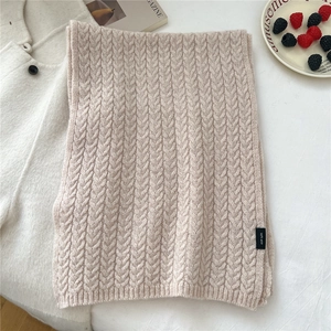 Close-up of beige cable knit wool scarf showing premium texture and 100% wool label