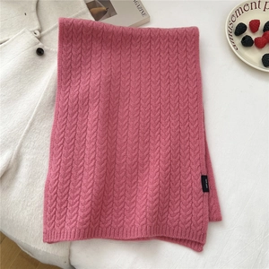 Detail of knit wool scarf in soft dusty pink with 100% wool label and cable texture