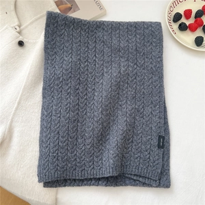 Detailed view of thick knit wool scarf texture with 100% wool material label