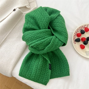 Close-up of green cable knit wool scarf texture with detail of a black woven label