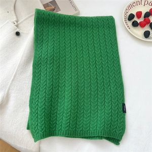 Close-up of green wool knit scarf with thick cable stitch and 100% wool label