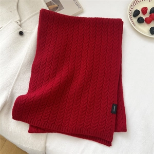 Detail of red wool scarf featuring classic cable knit texture and 100% wool material label
