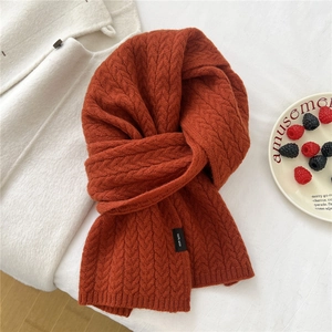 Detail of red-brown wool scarf featuring a classic cable knit texture and 100% wool label