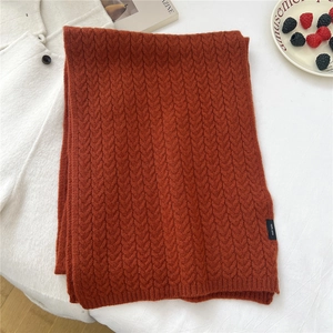 Detail of burnt orange 100% wool knit scarf with thick cable stitch texture and 100% WOOL tag