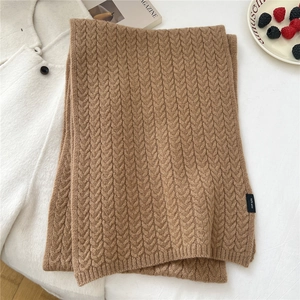 Detail of camel wool knit scarf showing 100% wool label and classic cable knit pattern