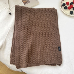 Close-up of thick dark brown knit wool scarf with 100% WOOL label and cable pattern