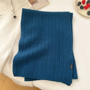 Detailed view of dark blue 100% wool scarf with chunky cable knit texture on white background