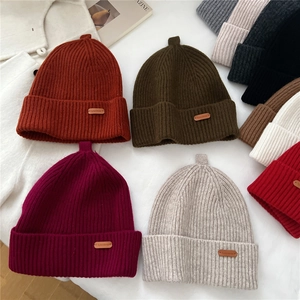 Chunky knit wool beanies in multiple colors with leather logo patches and ribbed texture