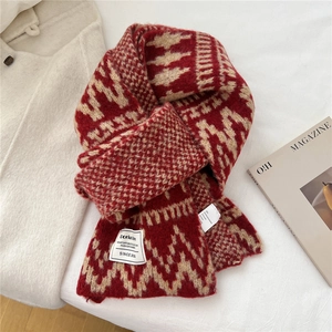 Close-up of geometric diamond pattern knit scarf with white woven brand label and texture