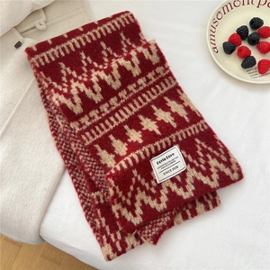 Detailed close-up of red and beige geometric jacquard knit scarf with woven brand label