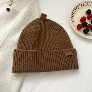 Detail of dark brown ribbed knit beanie featuring an embossed Epmetheus leather patch label