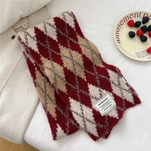Close-up of geometric argyle knit scarf featuring a white woven label and soft texture