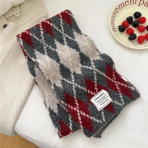 Close-up of red and grey argyle knit scarf with soft texture and brand label detail