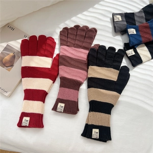 Close-up of striped knitted winter gloves with soft texture and brand woven label
