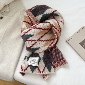 Detailed close-up of thick geometric diamond pattern knit scarf with brand label