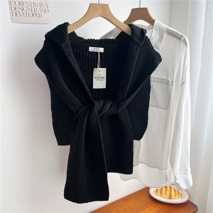 Detailed knit texture and authentic brand tag on a black fashionable knitted shawl cape