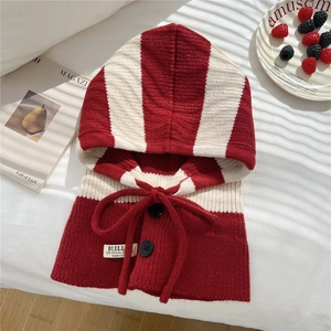 Detail of red and white striped knit balaclava featuring adjustable drawstrings and buttons