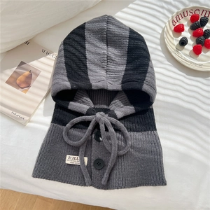 Detail of grey striped knit balaclava with buttons and drawstrings on white fabric