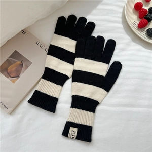 Detailed macro of black and white striped knit gloves with ribbed cuffs and woven label