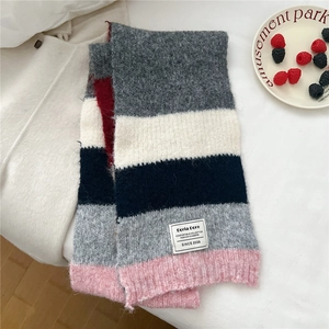 Détail de l'écharpe en maille rayée multicolore avec étiquette tissée sur fond doux