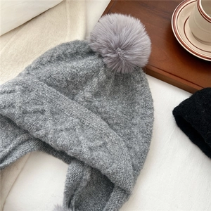 Thick grey cable knit beanie with pom-pom and ear flaps for winter warmth and comfort