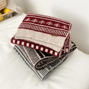 Close-up of wool blend knit scarves with Christmas tree patterns and leather label detail