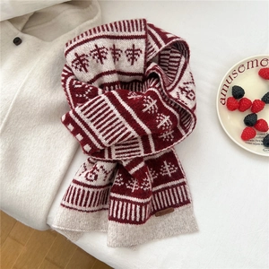 Detailed knit texture of red and white Fair Isle wool blend scarf with a small leather tag