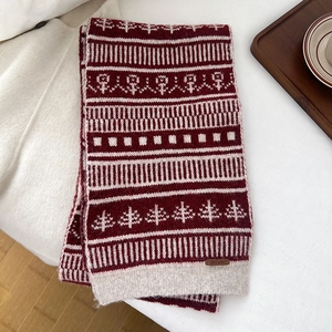 Detail of red and white knit scarf with Nordic Christmas patterns and leather logo tag