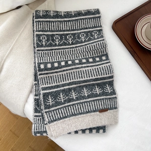Detail of wool blend knit scarf featuring pine tree pattern and leather brand tag