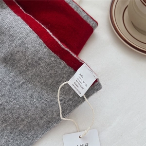 Detail of 100% pure wool scarf with two-tone red and grey contrast stitching texture
