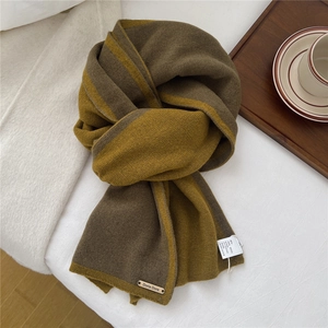 Detailed close-up of 100% wool knit scarf in two-tone brown and green with leather label