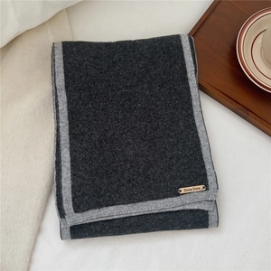 Close-up of thick knitted wool scarf with dual-tone grey borders and branded leather patch
