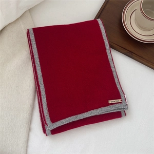 Close-up of a burgundy knit wool scarf with grey trim and branded Doria Dore label