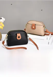 Close-up of contrast pebble leather crossbody bags with gold hardware and dual zippers