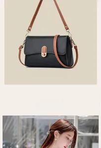 Detail of black pebbled leather crossbody bag with brown strap and gold metal lock