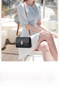 Detail of black pebbled leather crossbody bag featuring gold twist lock and white stitching