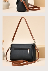 Detail of minimalist black pebbled leather mini crossbody bag with gold zipper and brown strap