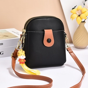Black litchi grain shoulder phone bag with brown strap and tiger charm in home setting