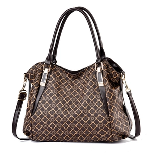 Detail of vintage clover pattern on brown faux leather handbag with gold metal hardware